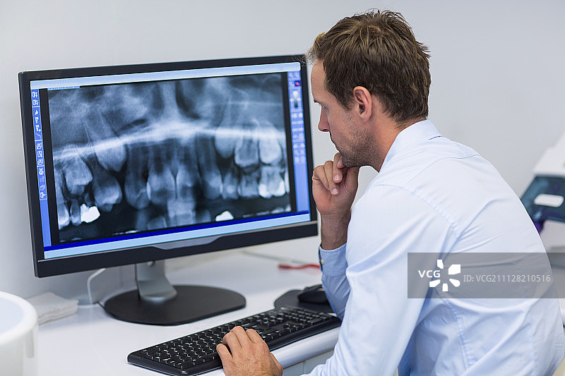 牙科医生在牙科诊所用电脑细心检查x光片图片素材