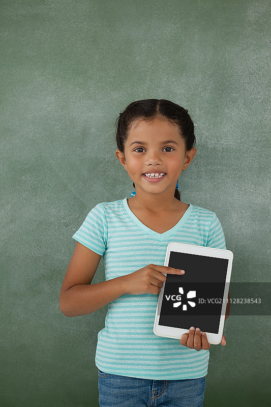 年轻的女孩拿着数字平板电脑对着黑板图片素材