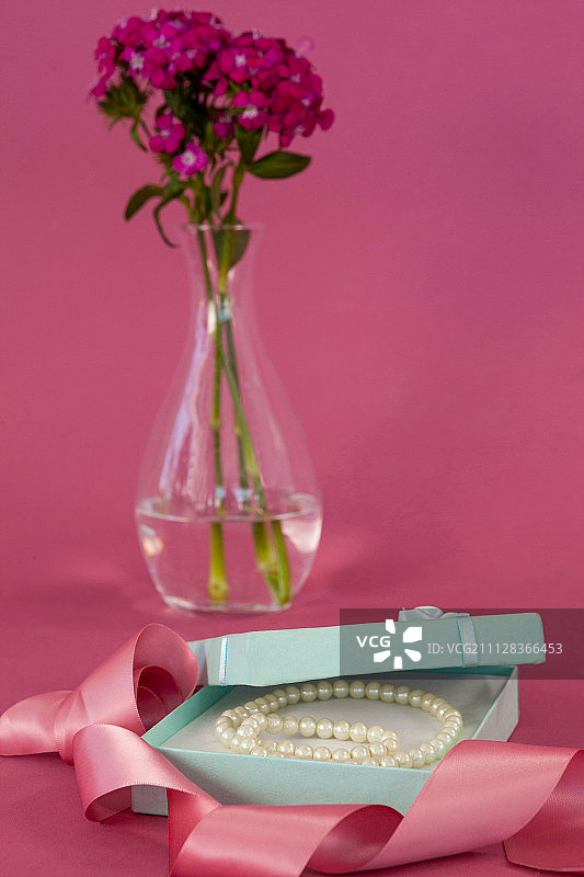 珍珠项链在打开的礼品盒粉红色的背景图片素材