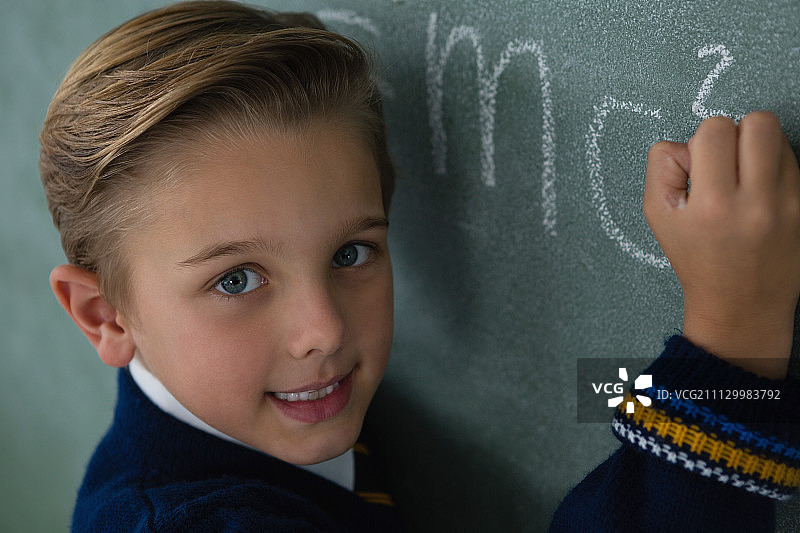 一个男生在黑板上写数学公式的肖像图片素材