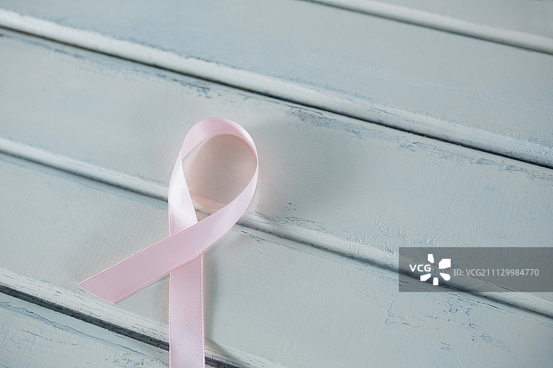 白色木桌上的粉色乳腺癌意识丝带的高角度视图图片素材