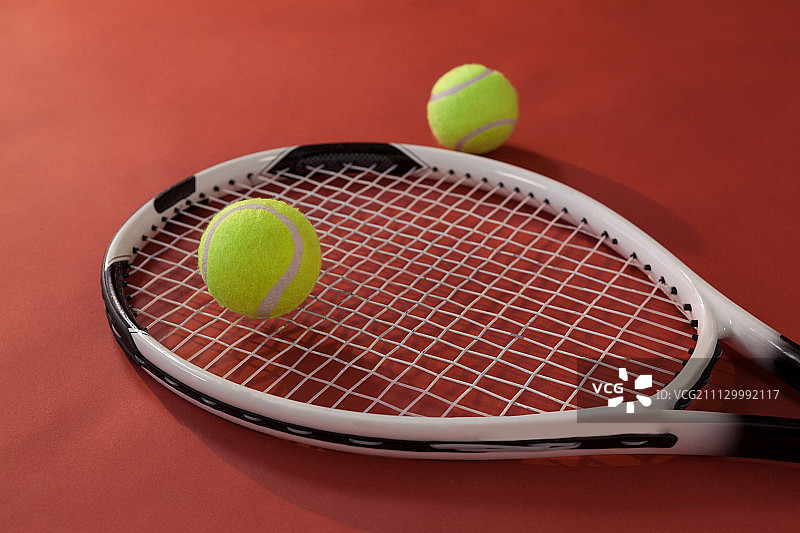 高角度的网球拍和荧光黄色球对栗色的背景图片素材
