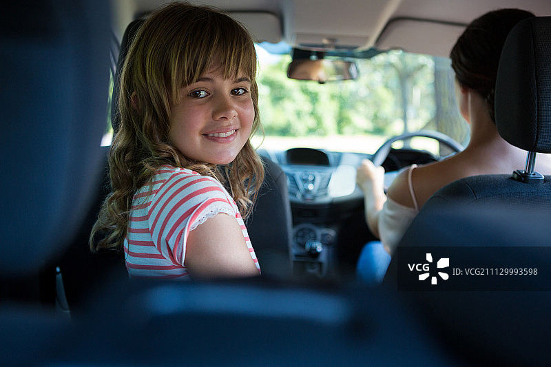 一个快乐的少女坐在后座上，一个女人在开车图片素材