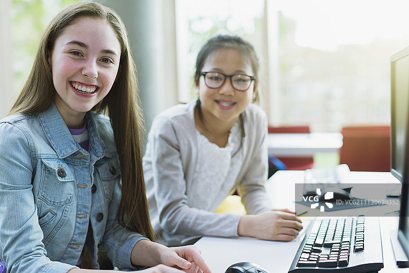 肖像微笑，自信的女学生在图书馆的电脑研究图片素材