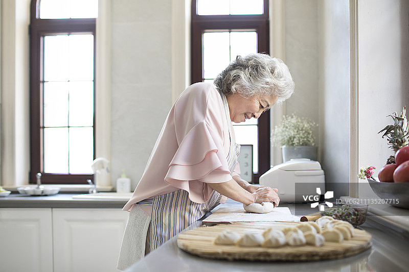快乐的老年女子在厨房包饺子图片素材