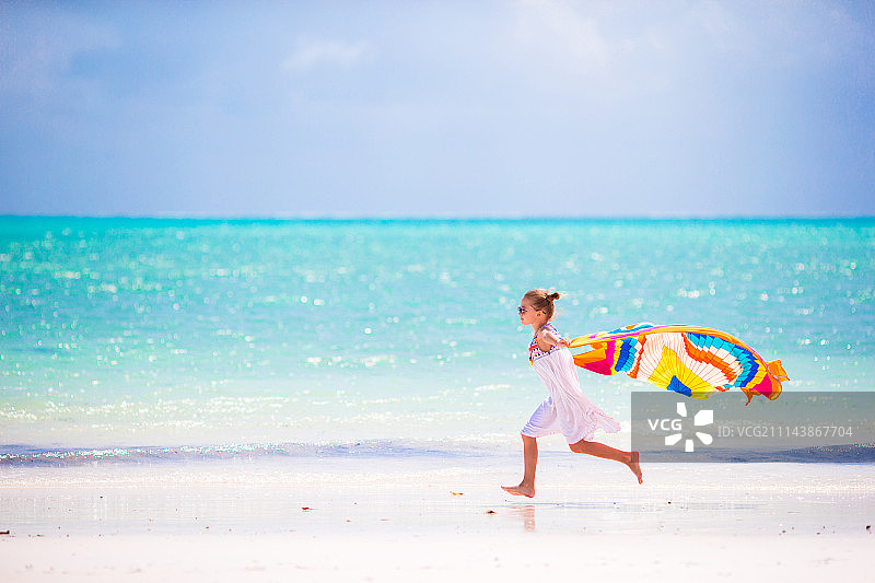 小女孩玩海滩浴巾在热带度假图片素材