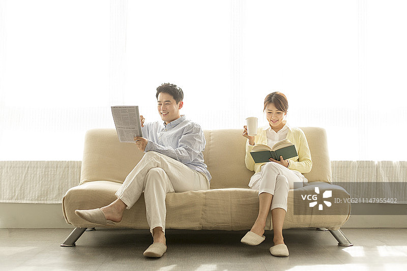 一对中年夫妇在沙发上看书看报纸图片素材