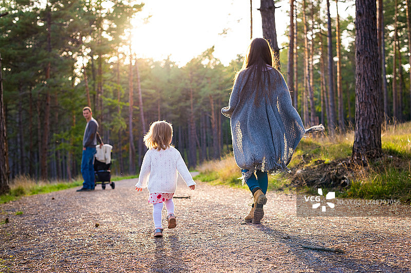 快乐的年轻家庭在公园散步，后视镜。一家人一起走在福雷斯特小路上…图片素材