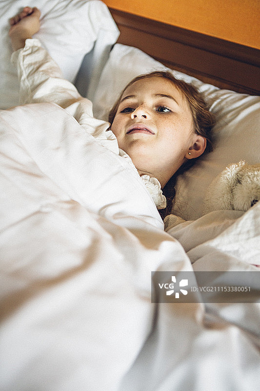 穿着睡衣的女孩抱着一个兔娃娃睡在床上图片素材