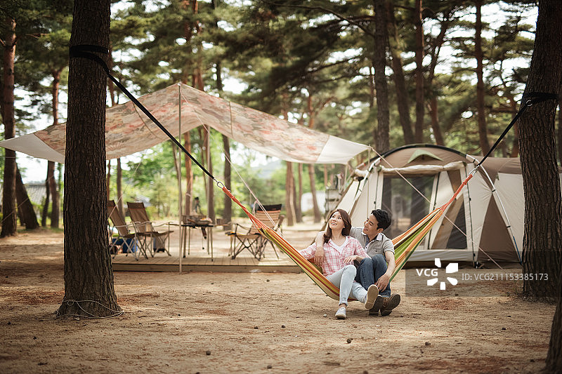 男人和女人坐在露营地点的吊床上图片素材