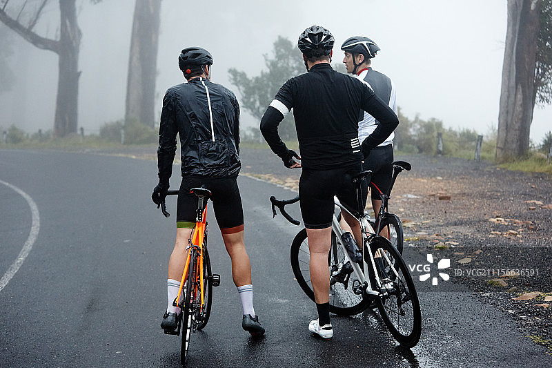 男性骑自行车的朋友们正在潮湿的路面上休息图片素材