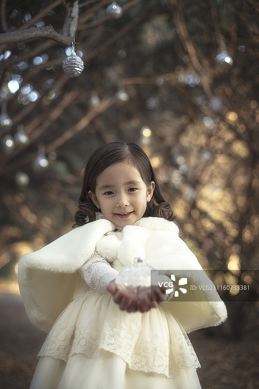 小女孩站在街上拿着冬季装饰的照片图片素材