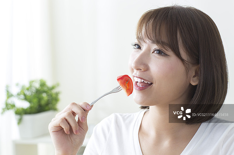 年轻女人吃蕃茄图片素材