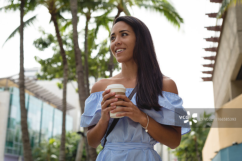 在街上拿着咖啡杯的漂亮女人图片素材