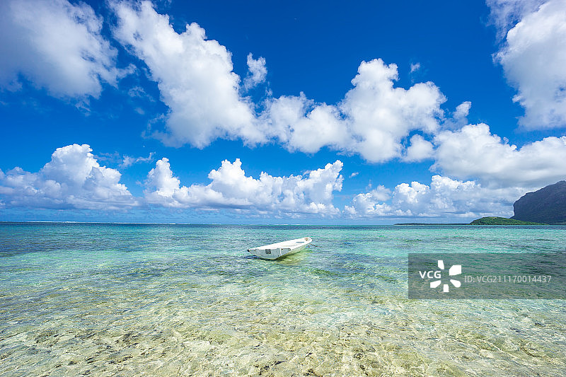 蓝色的天空，雪白的云和透明的海水映衬着白色的渔船。毛里求斯……图片素材
