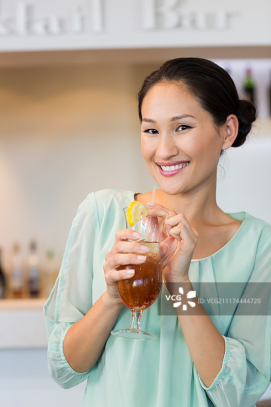 微笑的年轻女子拿着鸡尾酒杯在酒吧图片素材