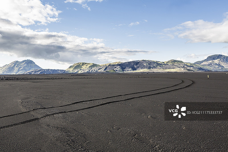 后板显示一个黑色的火山沙漠景观与汽车轨道在冰岛图片素材