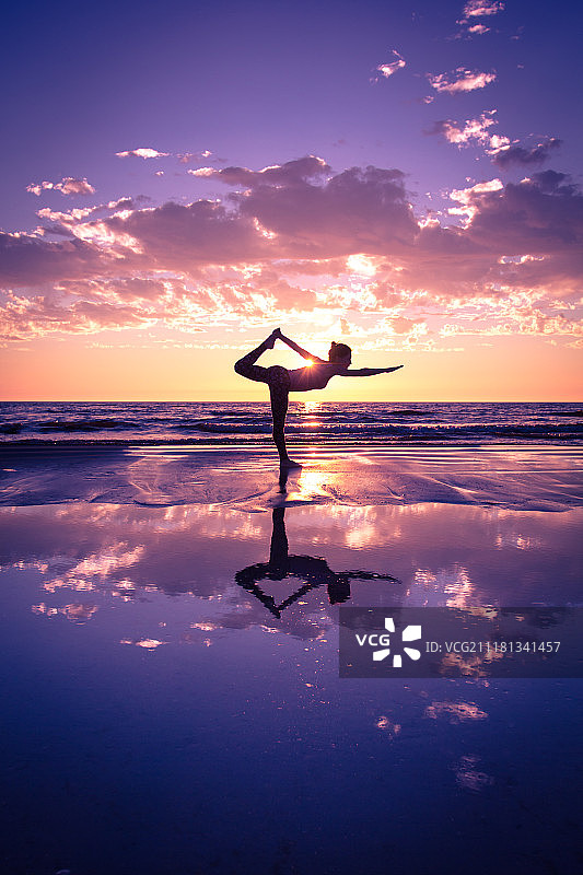 练习瑜伽的女人。日落时分，在海滩上练习瑜伽的女人的剪影图片素材