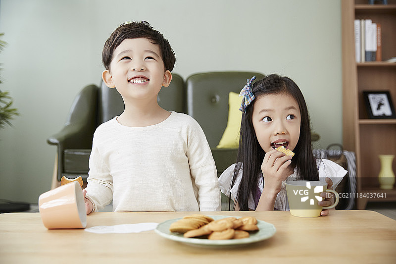 小男孩和小女孩吃糖果，把牛奶洒在桌子上图片素材