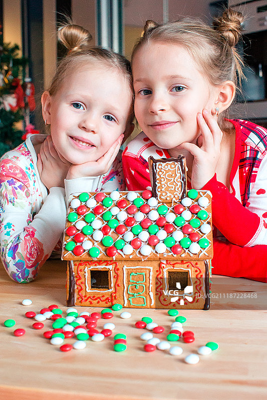 小女孩做圣诞姜饼的房子在壁炉装饰客厅图片素材