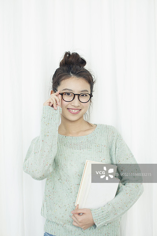 微笑的年轻女子拿着书图片素材