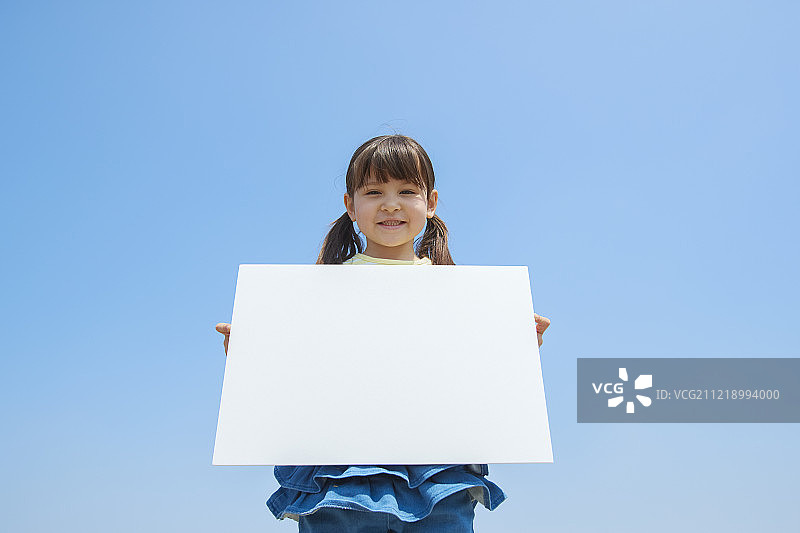 年轻的日本女孩拿着白板和蓝天图片素材