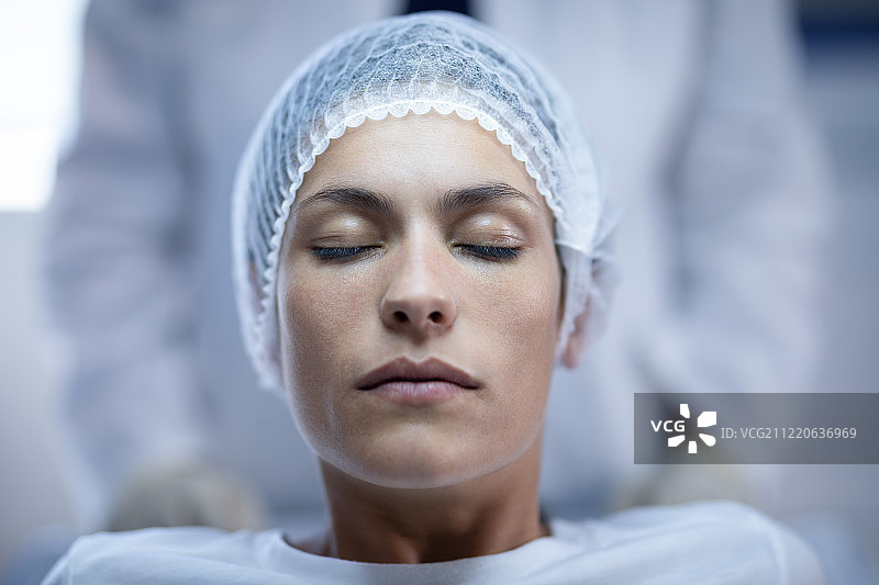 一位白人女性病人坐在医院的床上闭着眼睛图片素材