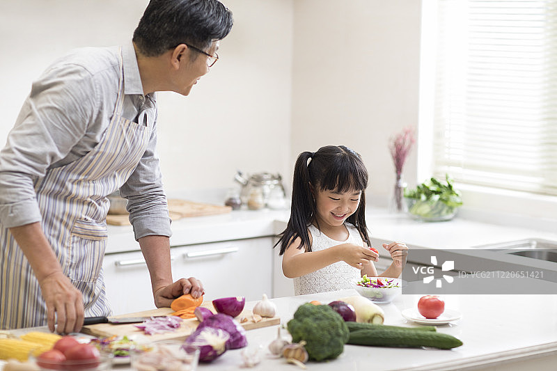 快乐小女孩和爷爷在厨房做饭图片素材