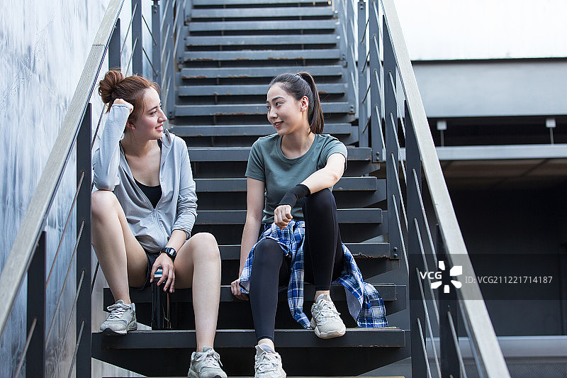 两个青年女子在户外运动后休息聊天图片素材