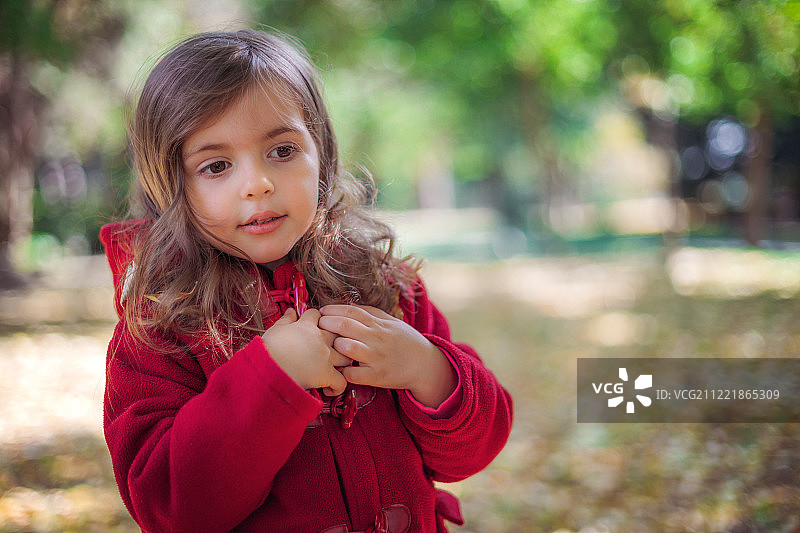 美丽的小女孩坐在秋天公园的落叶里图片素材