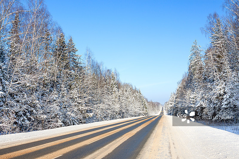 柏油路、森林和蓝天的冬季景观图片素材