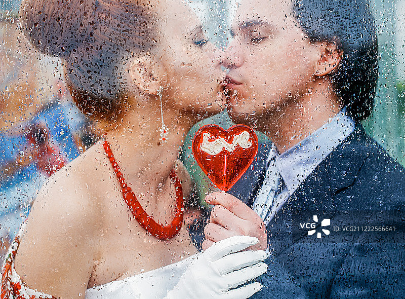 透过湿漉漉的玻璃在雨后的水滴中亲吻的情侣图片素材