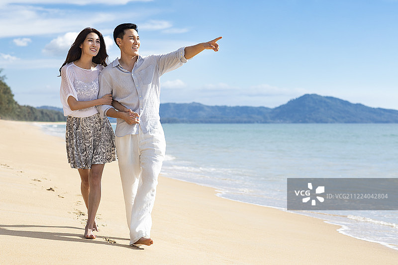 快乐的年轻夫妇在沙滩散步图片素材