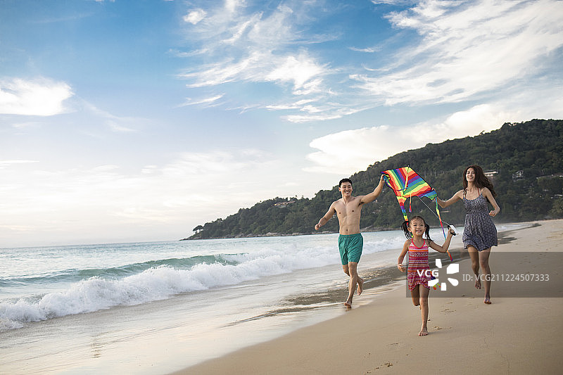 快乐的年轻家庭在沙滩放风筝图片素材