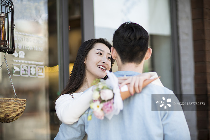 年轻女子手拿鲜花拥抱男朋友图片素材