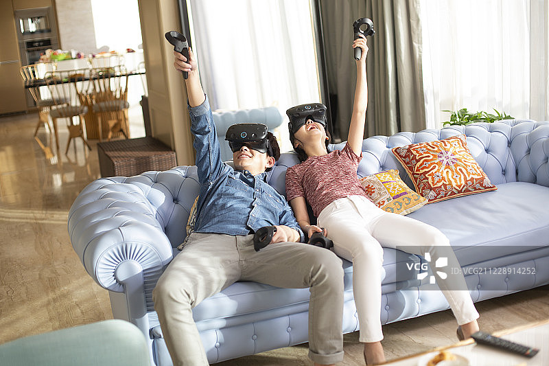 年轻情侣在家玩VR游戏图片素材