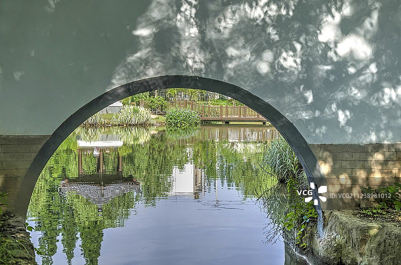 阳光墙拱下水中绿植映衬下的凉亭栈桥倒影图片素材