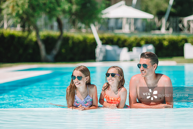 快乐的四口之家在户外游泳池图片素材
