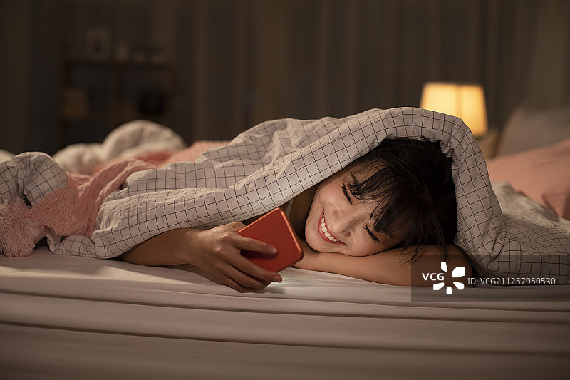 年轻女士睡前玩手机图片素材