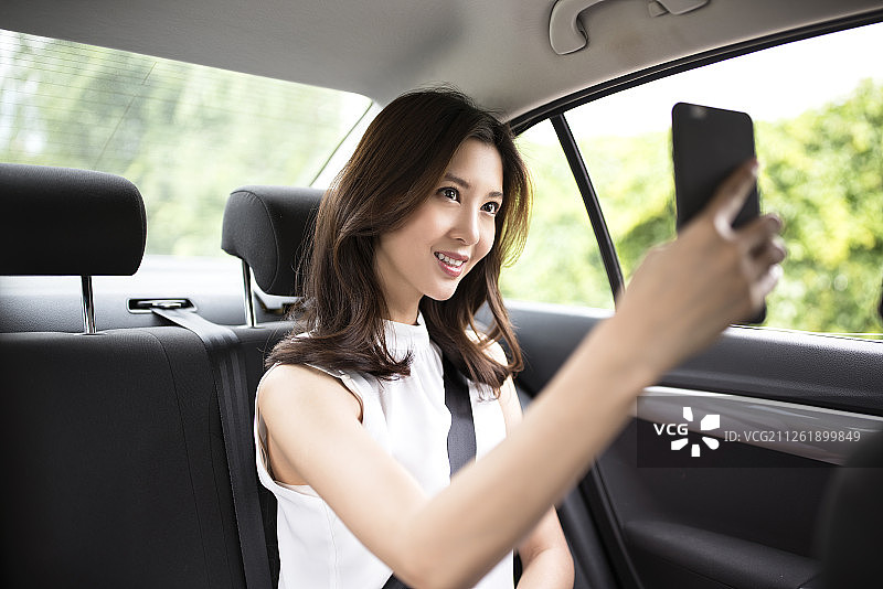 年轻女子在车内使用手机自拍图片素材