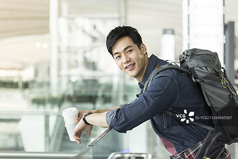 青年男子背着旅行包拿着咖啡在机场休息等候飞机起飞图片素材