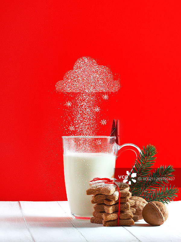 一杯牛奶与姜饼饼干在红色的墙壁背景与云下雪的图片图片素材
