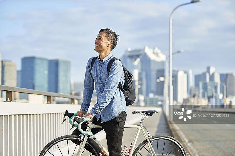 日本大阪市区，成熟的日本男人骑着自行车图片素材
