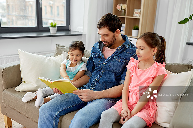 家庭、休闲、为人理念——快乐父亲带女儿在家读书。快乐的父亲带着女儿在家看书图片素材