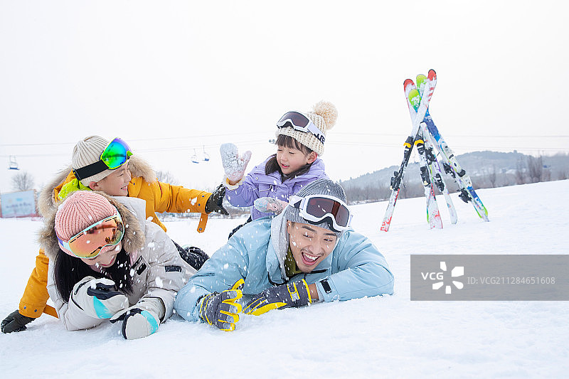 快乐的一家四口趴在雪地上打雪仗图片素材