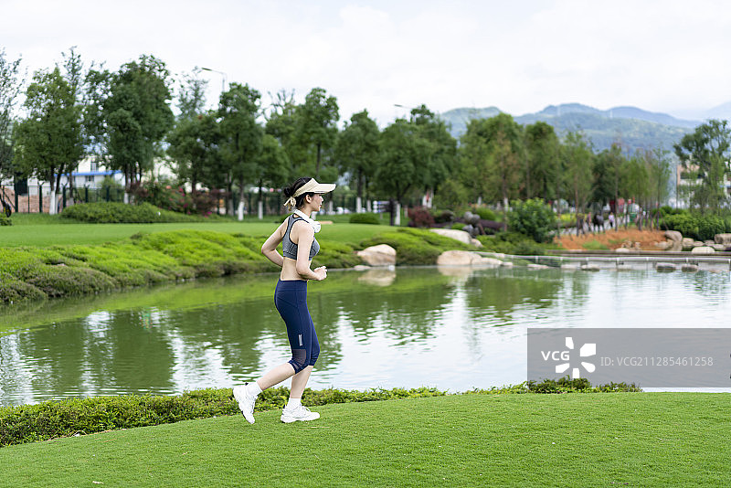 一个穿着运动服的年轻女性在湖边跑步图片素材