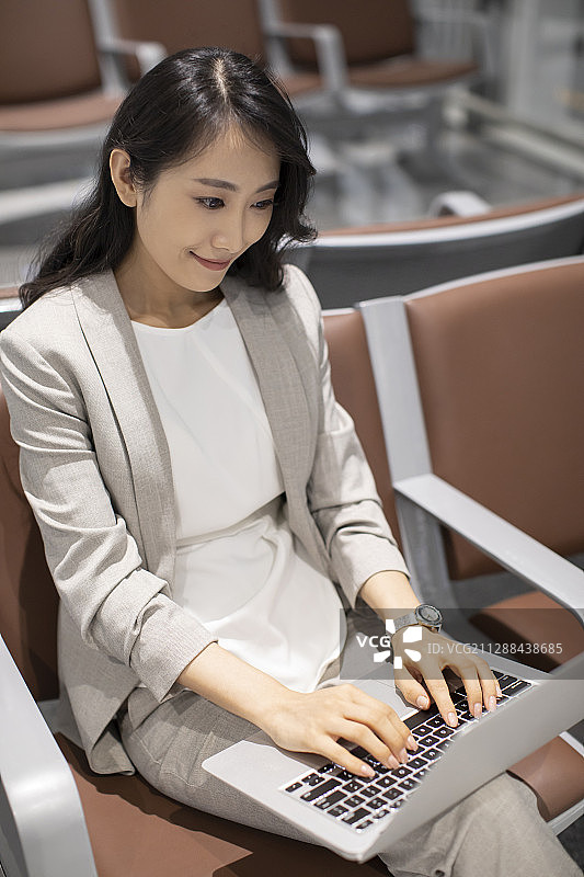 年轻商务女士在机场使用笔记本电脑图片素材