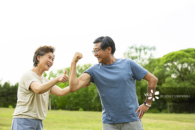 老年男人展示肌肉和老年女人点赞在户外公园运动后图片素材