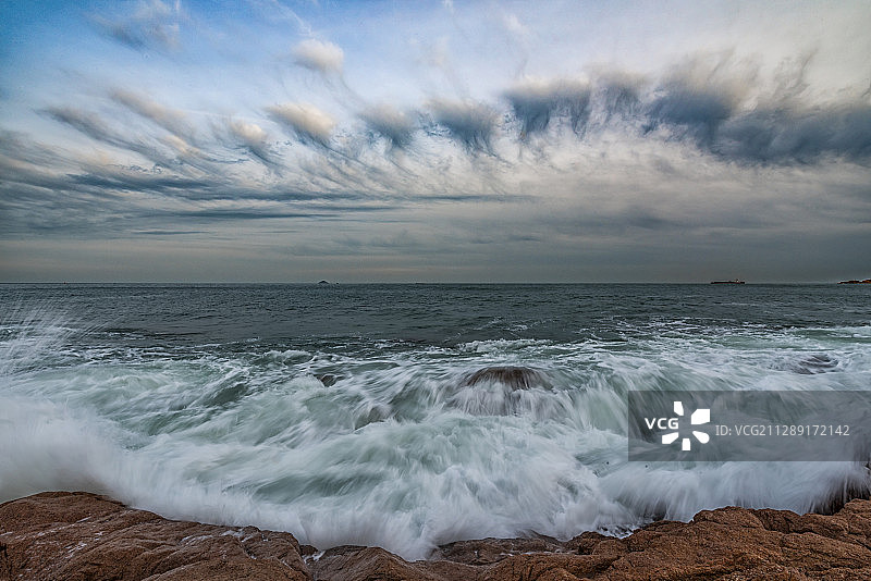 浪花飞舞的大海和蓝天上放射状彩云图片素材