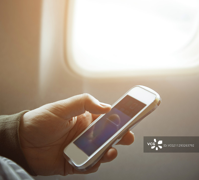 一个人拿着智能手机站在飞机窗口图片素材